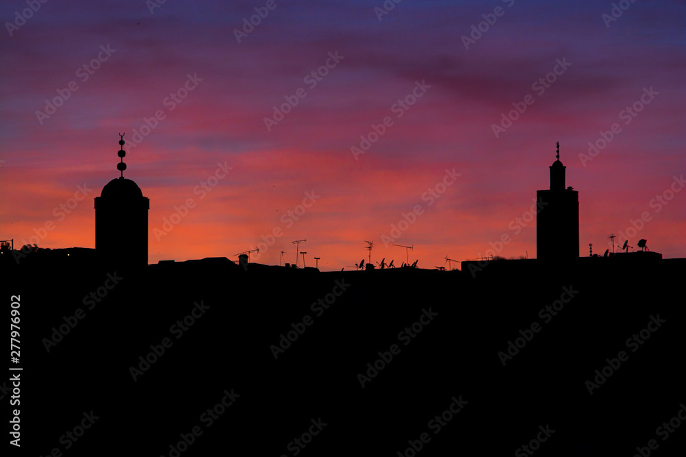 Violet sunset above moroccan city Fes with silhouette of minarets