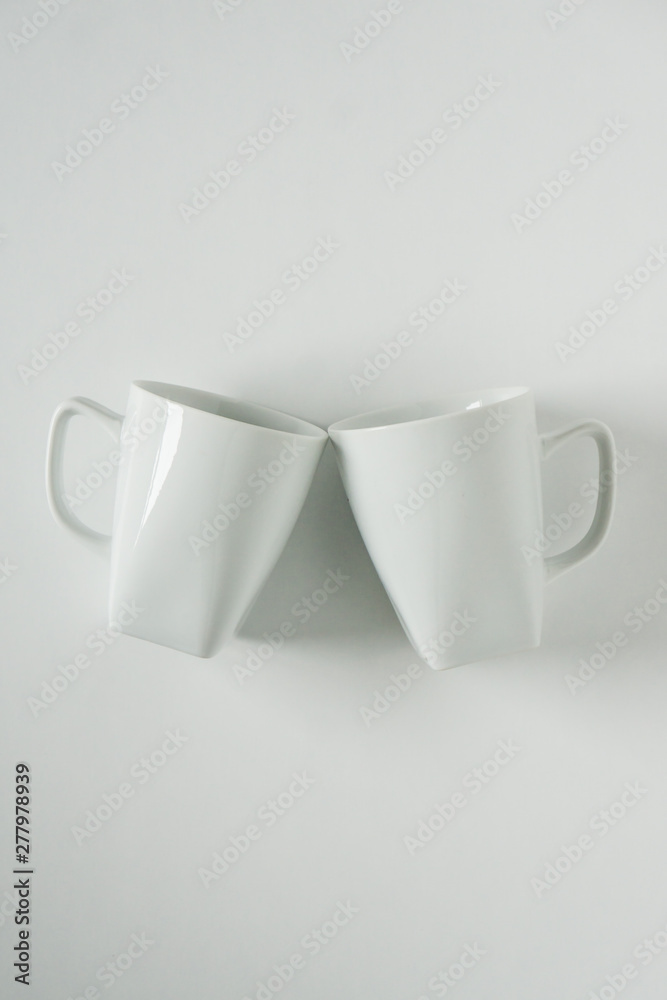 White coffee mugs on white background clinking in cheers with empty copy space White coffee mugs on white background clinking in cheers with empty copy space