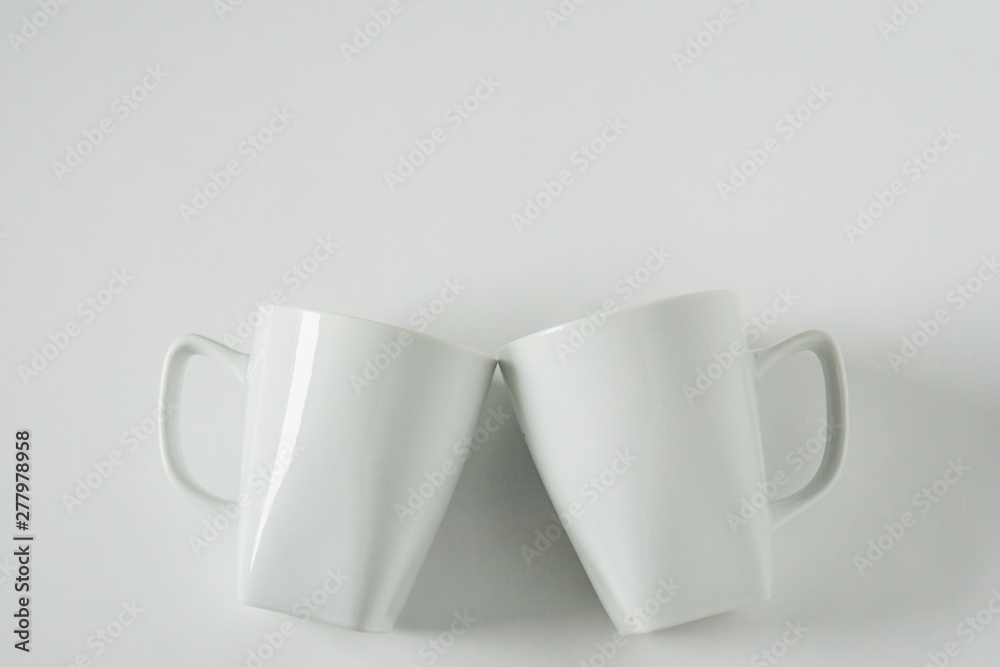 White coffee mugs on white background clinking in cheers with empty copy space White coffee mugs on white background clinking in cheers with empty copy space