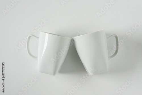 White coffee mugs on white background clinking in cheers with empty copy space