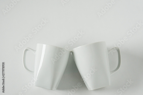 White coffee mugs on white background clinking in cheers with empty copy space