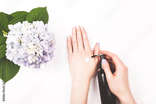 Woman holding a creamor lotion bottle in hands. Home spa  beauty and treatment concept. Flat lay  top view. Copy space.