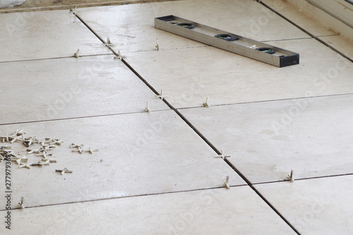 laying floor tiles. square tile light color. lifestyle image.