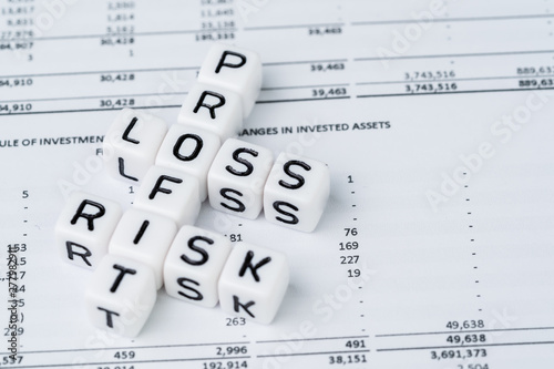 Risk  profit and loss in investment concept  small white cube block with alphabet building the crossword word mainly as Profit with the word Loss and Risk on financial investment reports