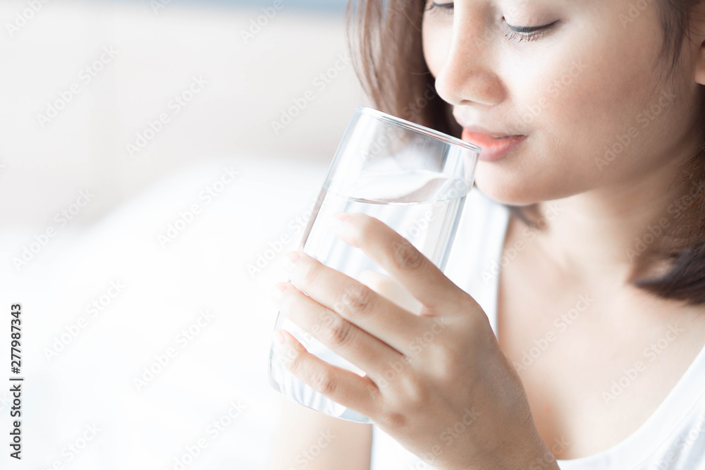 Close up woman drinking pure water from glass with light in the morning, Selective focus Close up woman drinking pure water from glass with light in the morning, Selective focus