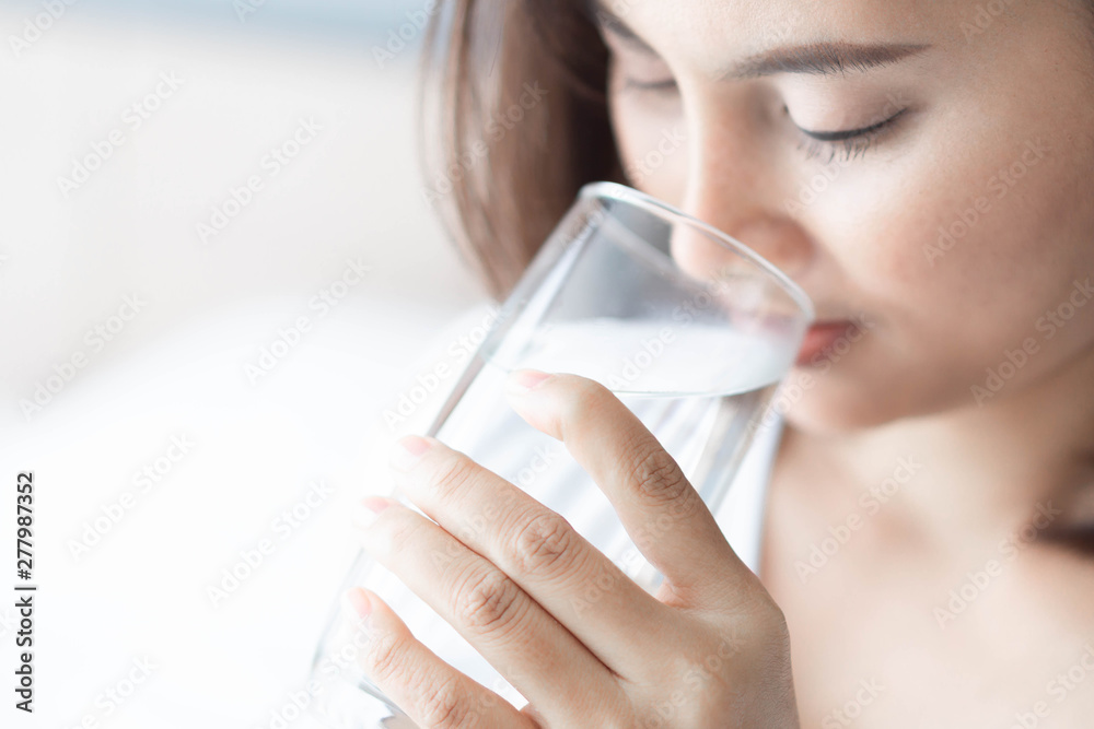 Close up woman drinking pure water from glass with light in the morning, Selective focus Close up woman drinking pure water from glass with light in the morning, Selective focus