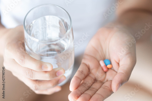 Closeup woman hand holding pills and glass of water, health care and medical concept, selective focus © mraoraor