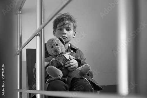 Fotografía Homeless little boy with teddy bear sitting indoors