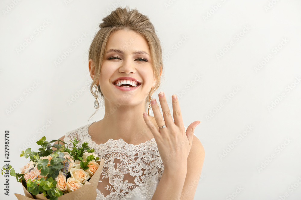 Beautiful young bride with bouquet of flowers showing her wedding ring on white background Beautiful young bride with bouquet of flowers showing her wedding ring on white background