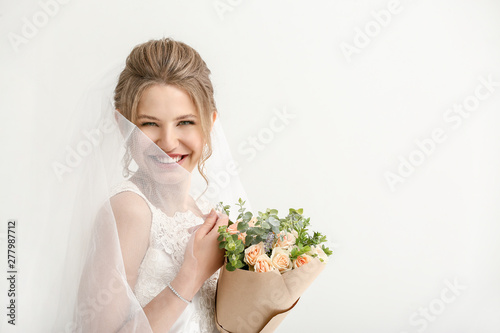 Beautiful young bride with bouquet of flowers on white background