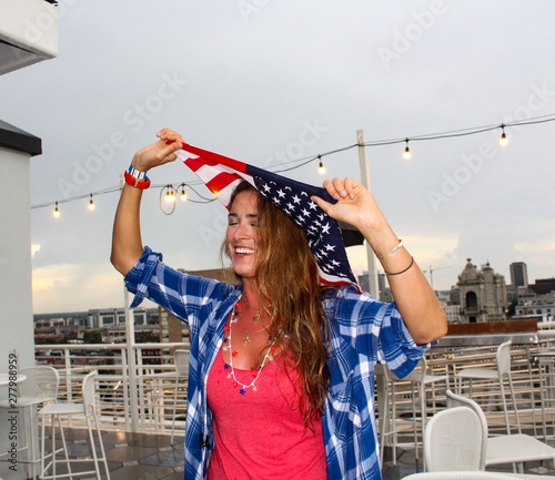 Beautiful Young American Millennial Woman Celebrating Fourth of July dressed in Red White and Blue with American Flag