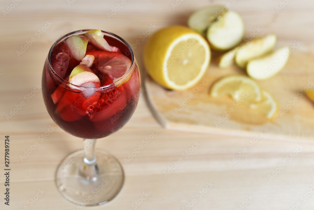 A glass of cold refreshing sangria with ice and fruit in water droplets.