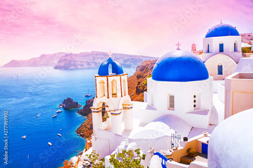 Beautiful sunset in the fabulous village of Oia with traditional white houses and blue domes of the church in Santorini, Greece