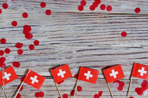 independence day Switzerland, August 1. Federal holiday in honor of the founding of the Swiss Confederation. day of the Confederacy. mini flags with confetti on wooden background. horizontal