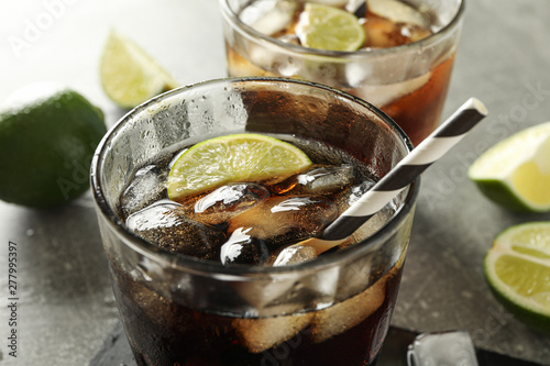 Glasses with cold cola and citrus on grey table, closeup