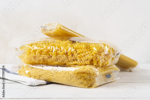 Various pasta in transparent plastic bags on a kitchen table.