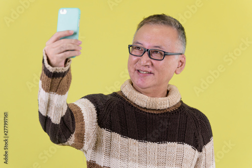 Happy mature Japanese man taking selfie ready for winter
