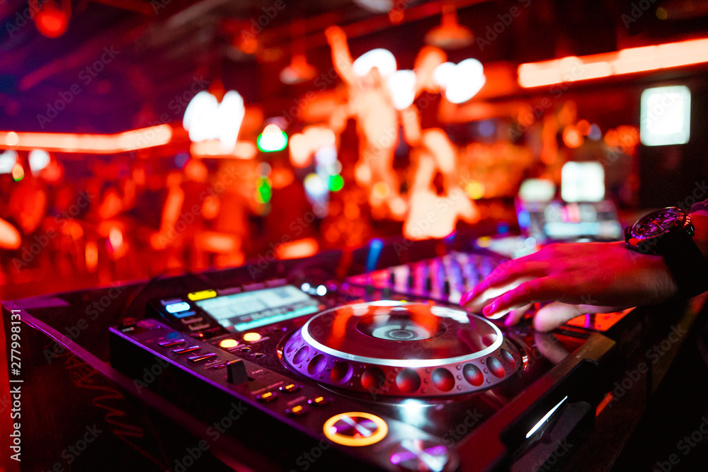 Dj mixing outdoor at beach party festival with crowd of people in  background - Summer nightlife view