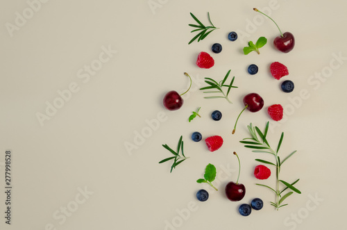 Fresh cherry, blueberry, raspberry, mint and rosemary leaf on top view with beige color background for healthy food concept.