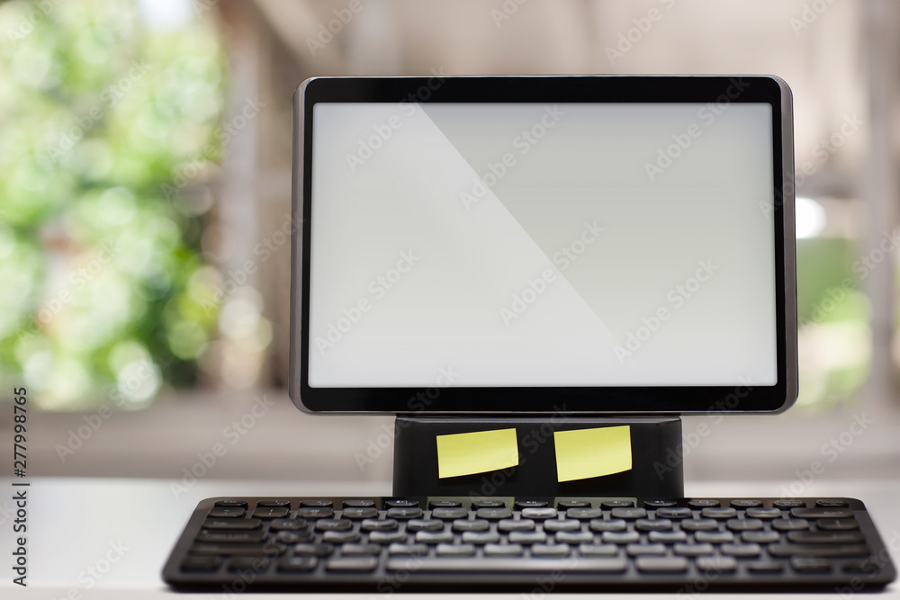 Fototapeta premium A computer with a touchscreen and wireless keyboard on a white desk with a window view in the background.
