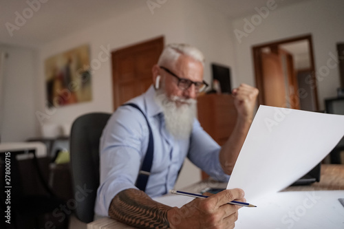 Good job! Businessman is celebrating the growth of company's income. His hand are raised with fist. Focus hand and papel - Image photo