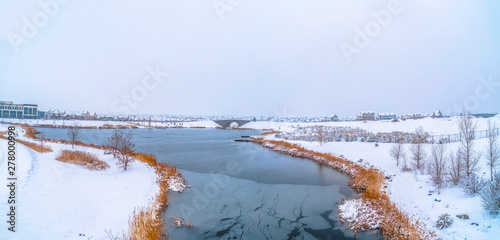 Frosty nature secnery with a lake surrounded by snowy terrain in winter photo