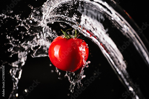 Tomato with water splash on black background 