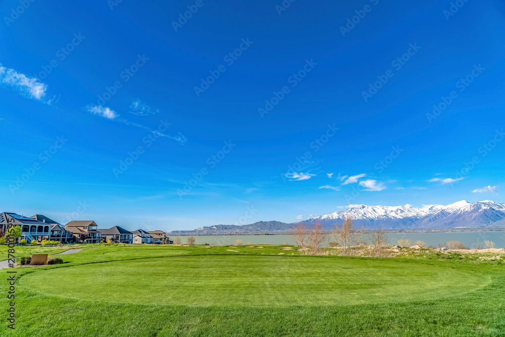 Homes and pathway on a vast field overlooking a lake and snow topped mountain Homes and pathway on a vast field overlooking a lake and snow topped mountain