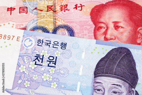 A blue two thousand won note from South Korea close up in macro with a red, one hundred yuan note from the People's Republic of China