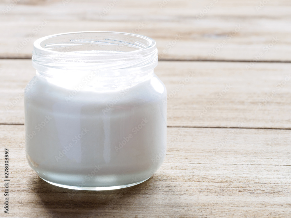 White cosmetic cream in a transparent jar on a brown wooden background White cosmetic cream in a transparent jar on a brown wooden background