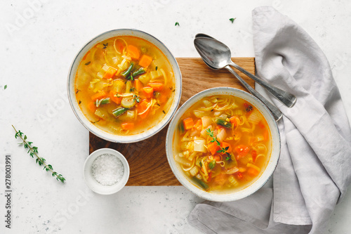 View from above on two portion of spring vegetable soup with chicken broth.