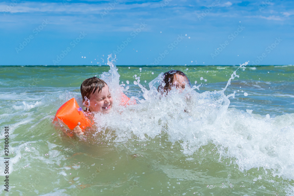 Mum with the small son float in the sea waves. A woman and a little boy are splashing in the water. Mum with the small son float in the sea waves. A woman and a little boy are splashing in the water.