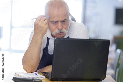 senior man sighing as he uses laptop