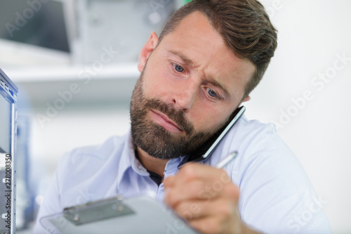 businessman holding mobile phone between ear and shoulder