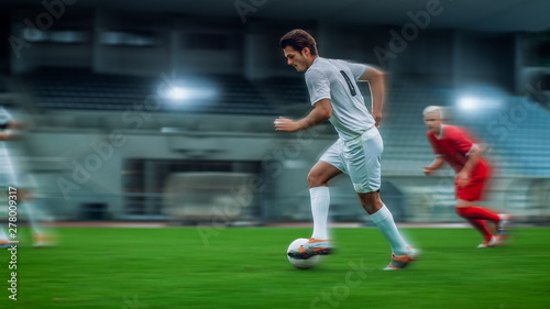 Blurred Motion Shot of Professional Soccer Player Leads with a Ball. Two Professional Football Teams Playing On a Stadium. © Gorodenkoff