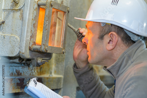 man looking through inspection glass of industrial incinerator