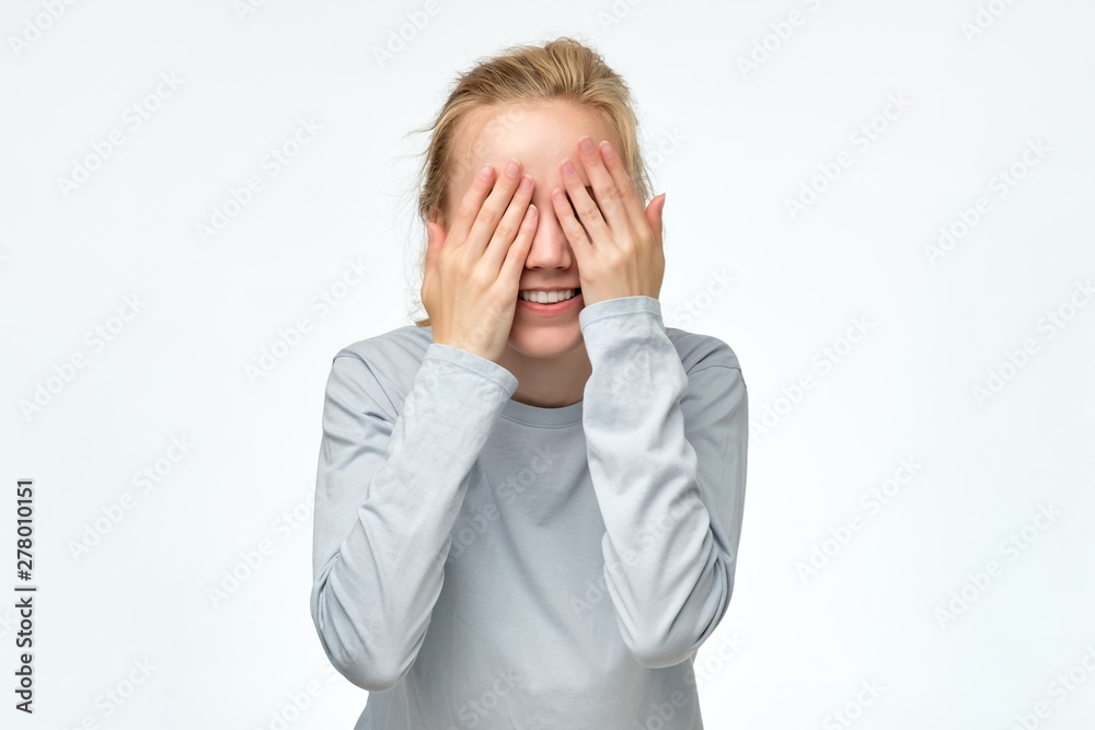 Young woman covering her eyes with her hands expecting to see a surprise on your birthday. Positive facial emotion studio shot Young woman covering her eyes with her hands expecting to see a surprise on your birthday. Positive facial emotion studio shot