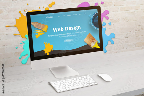 Concept of web design studio with coimputer display and color drops on brick wall. Modern web design teme on screen. Concept of modern graphic studio desk.