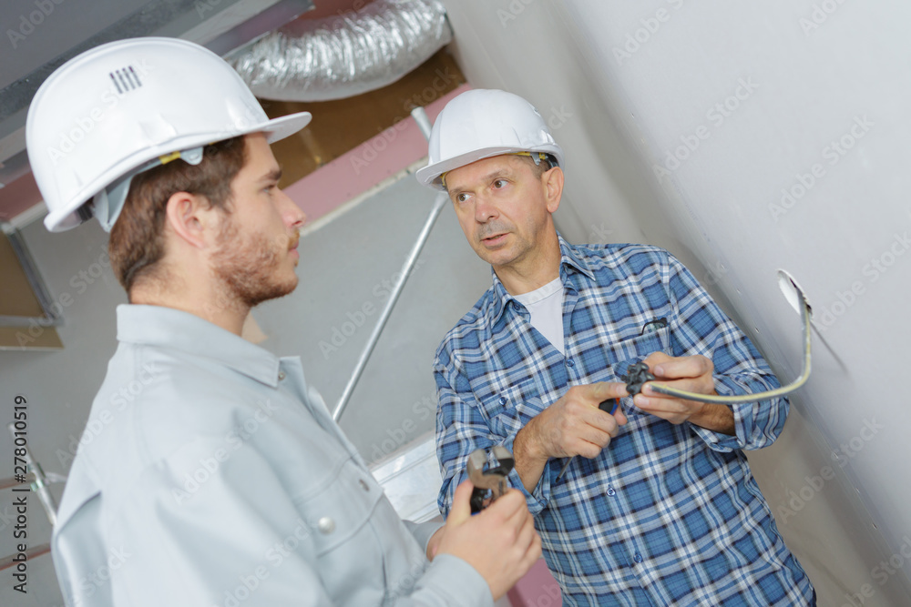 foreman showing dismantled socket to eapprentice electrician foreman showing dismantled socket to eapprentice electrician