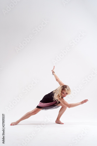 Image of dancing young long-haired woman blonde looking down in black dress in studio isolated