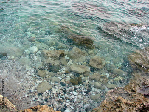 The view from the shore to the seabed is covered with large sharp rocks through the thickness of the transparent azure water of the Mediterranean Sea. © Hennadii