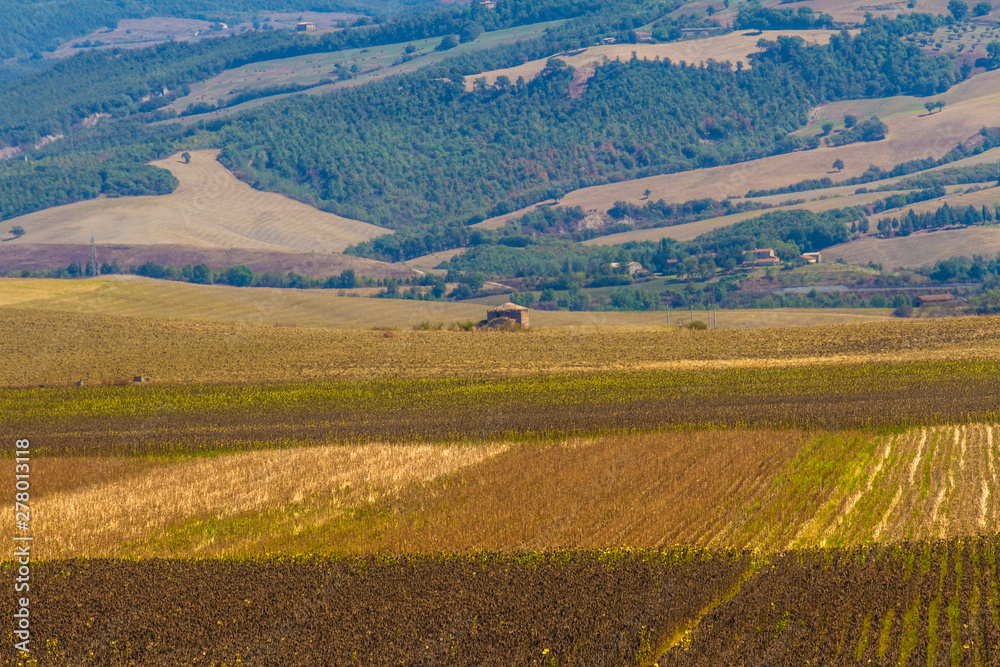 Tuscan countryside at the end of summer: fields worked with a small house and some hills in the background