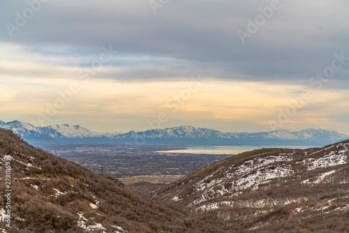 Lake and vast valley viewed from a mountain with trees and snow