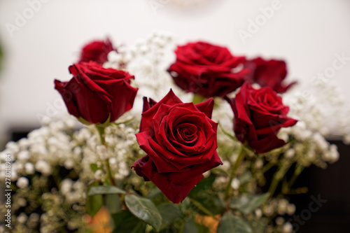 Bunch of seven beautiful red roses standing on a wooden table