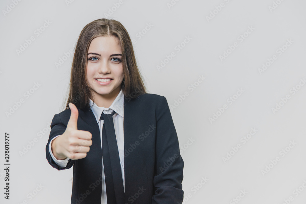 Female hand gestures thumb up. Business girl is smiling broadly and shares positive emotions. Female hand gestures thumb up. Business girl is smiling broadly and shares positive emotions.