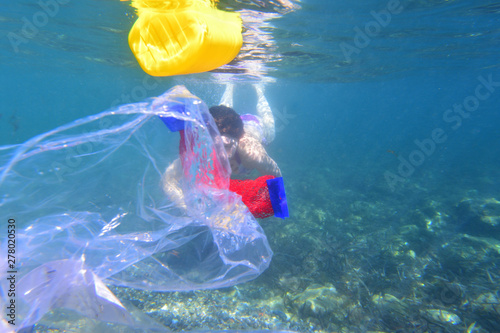 woman diving in the sea with garbage, plastic