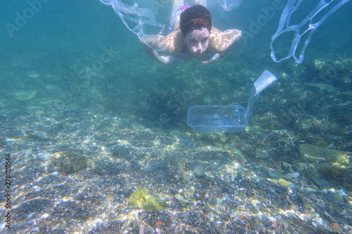 woman diving in the sea with garbage
