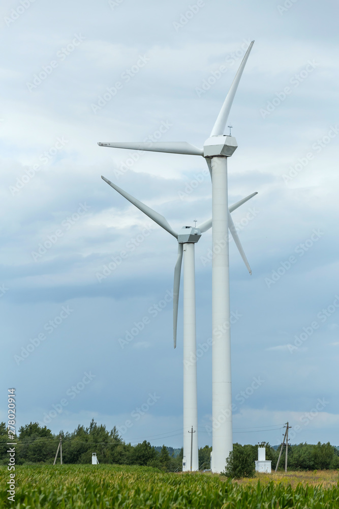 Pair of wind turbines against a sky with clouds. Clean energy for the agro farm. Pair of wind turbines against a sky with clouds. Clean energy for the agro farm.