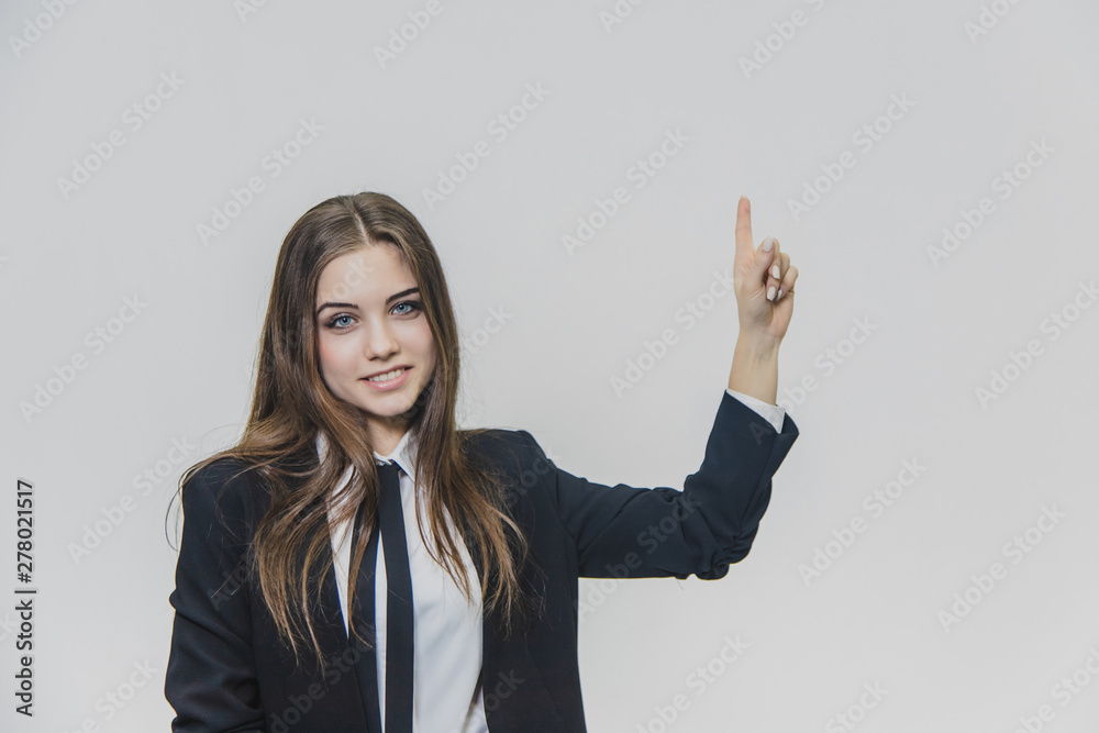Young, pretty businesswoman is pointing her finger up with a positive facial expression. Young, pretty businesswoman is pointing her finger up with a positive facial expression.