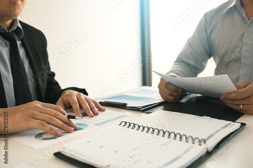 Two business partnership coworkers analysis strategy and gesturing with discussing a financial planning graph and company budget during a budget meeting in office room.